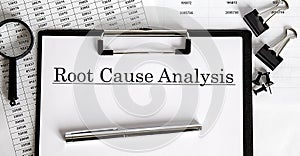 White sheet with the text of the Root Cause Analysis on the background of documents and graphs