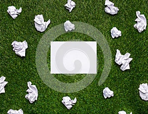 White sheets of paper with cramled sheets lying on the grass