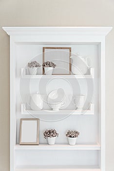 White shelf with vintage porcelain tableware in house.