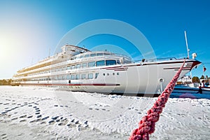 White ship stands at the shore in the ice of the river in a winter sunny day.