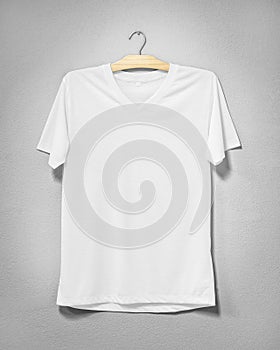 White shirt hanging on cement wall. Empty clothing for design. Front view