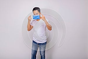 A white shirt Thai man is wearing a blue mask