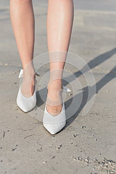 White shoes on the girl`s feet. The legs in the shoes are close-up. A girl in fashionable shoes walks through the city. Asphalt