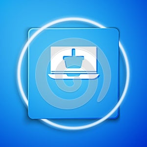 White Shopping basket on screen laptop icon isolated on blue background. Concept e-commerce, e-business, online business