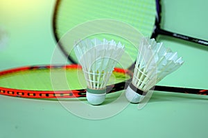 white shuttlecock on green background, blurred badminton racket and white shuttlecocks background.