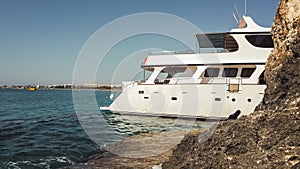 White sightseeing boat plows behind the rock. Pleasure boat cruising between the rocks. Vacation on tropical islands