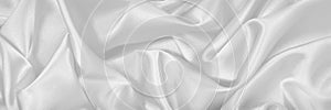 White silk satin fabric. White elegant background. Dark liquid wave or black silk with wavy folds.