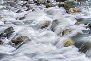 White silky water flowing downstream over the rocks and boulders photo