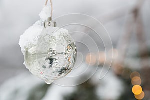White Silver Beautyful Christmas Ornament Bauble haning at a Fir Tree with Snow