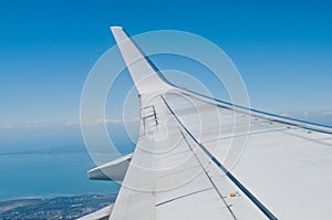 White silver plane wing flying in blue sky