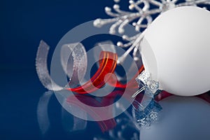 White, silver and red christmas ornaments on dark blue background