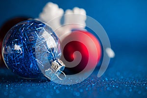 White, silver and red christmas ornaments on dark blue glitter background.