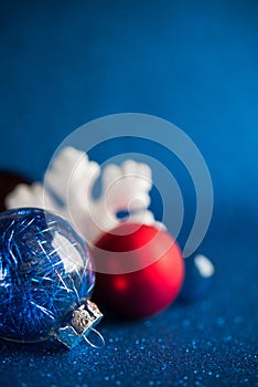 White, silver and red xmas ornaments on dark blue glitter background with space for text.