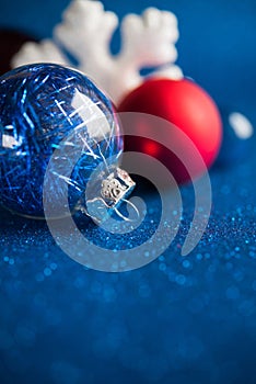 White, silver and red xmas ornaments on dark blue glitter background with space for text.