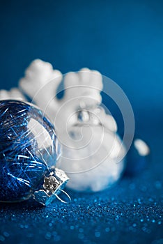 White and silver xmas ornaments on dark blue glitter background with space for text