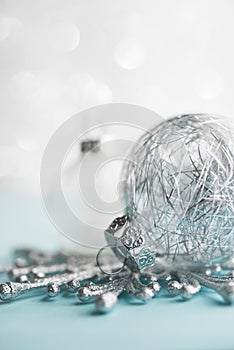 White and silver xmas ornaments on glitter bokeh background. Merry christmas card.