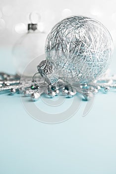 White and silver xmas ornaments on glitter bokeh background. Merry christmas card.
