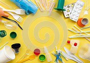 White single-use plastic and other plastic items on a yellow background photo