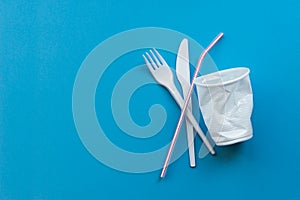 White single-use plastic and plastic drink straws on a blue background. Say no to single use plastic