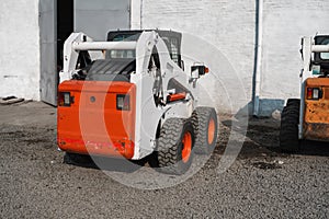 White skid steer loader at a construction site waiting of work. Industrial machinery. Industry.