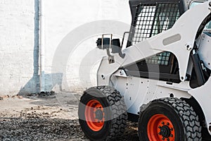 White skid steer loader at a construction site waiting of work. Industrial machinery. Industry.