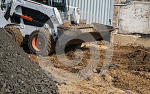 White skid steer loader at a construction site working with a soil. Industrial machinery. Industry.