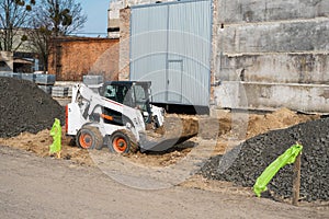 White skid steer loader at a construction site working with a soil. Industrial machinery. Industry.