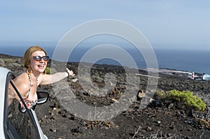 White skin passenger woman out of the window in an automobile in bikini and sunglasses on a rent a car.