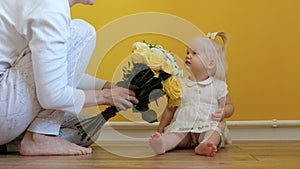 A white-skinned girl is sitting on the floor and looking at the camera on a yellow background.