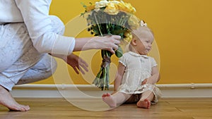 A white-skinned girl is sitting on the floor and looking at the camera on a yellow background.