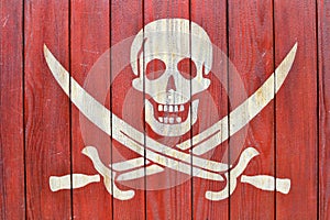 A white skull with swords symbolizing pirates on a red wood background