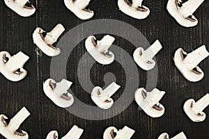 White sliced mushrooms on black wood rustic background, top view