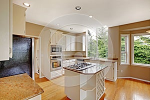 White small classic American kitchen interior with kitchen island and granite counter top.