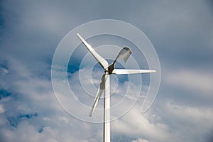 White small eolian wind turbine close up, blue sky with white clouds