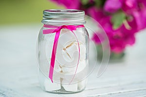 White small marshmallows in a glass pot on wooden table. Selecti