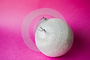 White small round glass plastic xmas festive Christmas ball, Christmas toy plastered over sparkles on a pink purple background