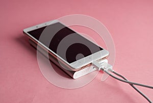 White smart phone charger with charger power bank on pink background