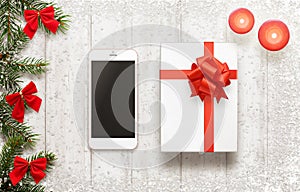 White smart phone and christmas gift on white board