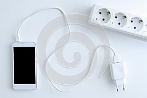 White smartphone battery charging cable and power outlet