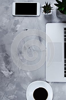 White smartphone with black blank screen on office desk with laptop and cup of coffee. Mock up of phone