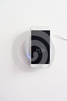 White smartphone charged by wireless charger