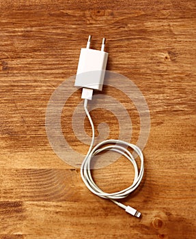 White smartphone charger over wooden board