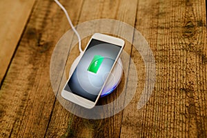 White smartphone charging on a charging pad.