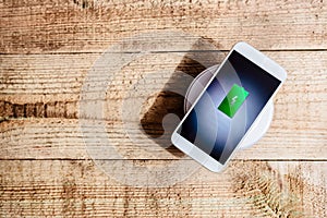 White smartphone charging on a charging pad.