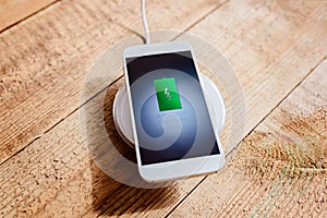 White smartphone charging on a charging pad.