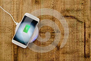 White smartphone charging on a charging pad.