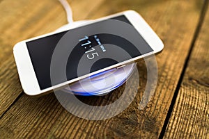 White smartphone charging on a charging pad.