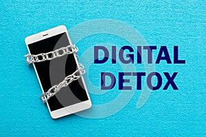 White smartphone with metal chain on blue background. Digital de photo