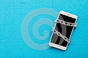 White smartphone with metal chain on blue background. Digital de photo