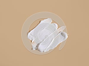 White smear of cosmetic cream on a beige background. Creamy foundation texture isolated. Smear of face cream. Close up